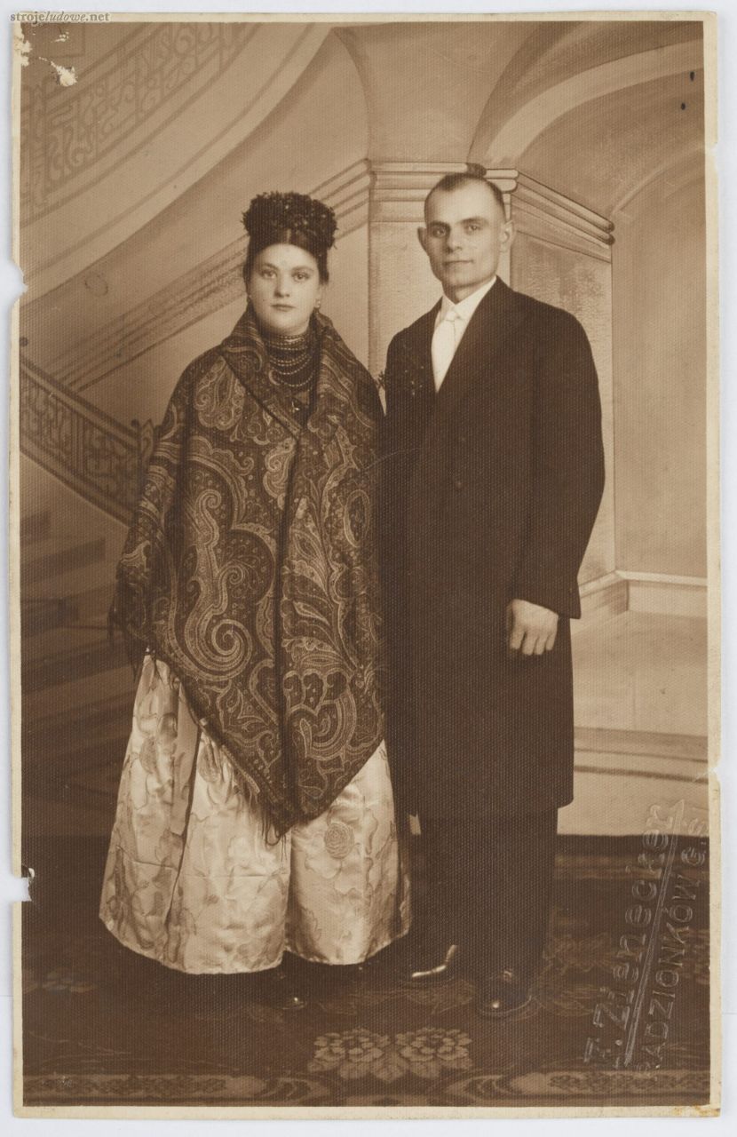 Nowożeńcy, kobieta w&nbsp;stroju rozbarskim ze&nbsp;szpiglem, mężczyzna w&nbsp;stroju miejskim, atelier F. Zienecker, Radzionków, lata 20. XX&nbsp;w. Ze&nbsp;zbiorów Muzeum Górnośląskiego w&nbsp;Bytomiu.