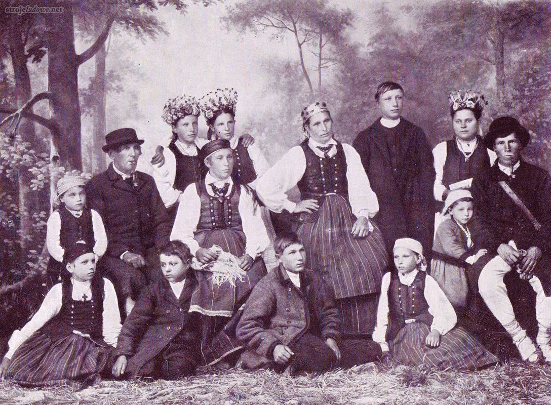 Kurpie z okolic Baranowa w strojach odświętnych, Ziemia, 1914 r., fot. F. Malinowski,
We tej wsi dziewczęta nosiły nieco inne niż w pozostałej części regionu nakrycie głowy.