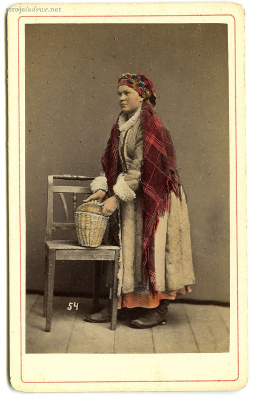 Kobieta w kożuchu, fot. I. Krieger, Archiwum Naukowe Państwowego Muzeum Etnograficznego w Warszawie

Ignacy Krieger, fotograf, od 1860 r. prowadził w Krakowie zakład fotograficzny. Specjalizował się w fotografii dokumentacyjnej, wśród której ważne miejsce zajmowały zdjęcia portretowe, wykonywane w atelier. Na fotografiach Kriegera, często ręcznie kolorowanych, pojawiają się tzw. „typy ludowe” w strojach regionalnych. Są to anonimowi modele przedstawiani w wystylizowanych pozach, a często w zaaranżowanych scenach rodzajowych z rekwizytami. Pomimo teatralności przedstawień, fotografie Ignacego Kriegera stanowią cenne źródło wiedzy na temat ubiorów chłopskich z okolic Krakowa, a także na temat spojrzenia na ludową kulturę w tamtym czasie.