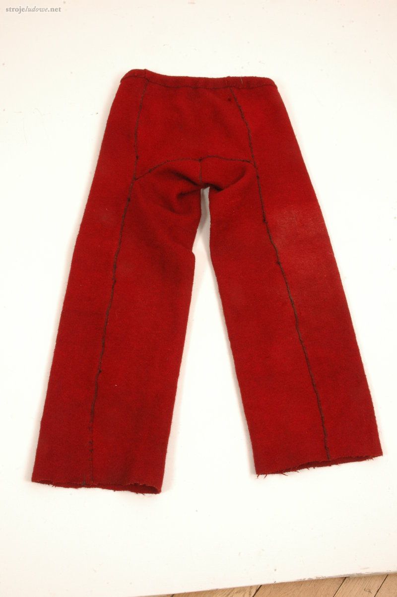 Spodnie (<em>kraszanyci</em>)<em>,</em> tył, okres międzywojenny, Huculszczyzna, ze zbiorów Muzeum Archeologicznego i Etnograficznego w Łodzi, fot. Wł. Pohorecki

Najstarsze spodnie, jakie noszono na Huculszczyźnie to długie szerokie spodnie z grubego białego płótna zwane <em>porkenyci</em>. Najpopularniejsze jednak, najczęściej opisywane w literaturze etnograficznej i podróżniczej, były szyte z czerwonego sukna tzw.<em> kraszanyci </em>lub<em> </em>czarne. Występowały również spodnie niebieskie, a czasem<em> </em>białe<em> </em>(<em>chołoszni, haczi</em>). Spodnie krojone były z jednej szerokości i długości sukna. Krój składał się z dwóch płatów sukna (<em>nogawic</em>), z przodu gładkich, złożonych i zachodzących na tył, pomiędzy które wszyte były dwa kliny (<em>kłynie</em>): jeden w kształcie trapezu, wszyty z tyłu portek, drugi w kształcie trójkąta, wszyty z przodu. Z przodu nogawice rozdzielał rozpór (<em>koczerha</em>)<em>.</em> Do połowy XIX stulecia wszystkie spodnie szyte były do <em>oczkura, </em>czyli pasa,