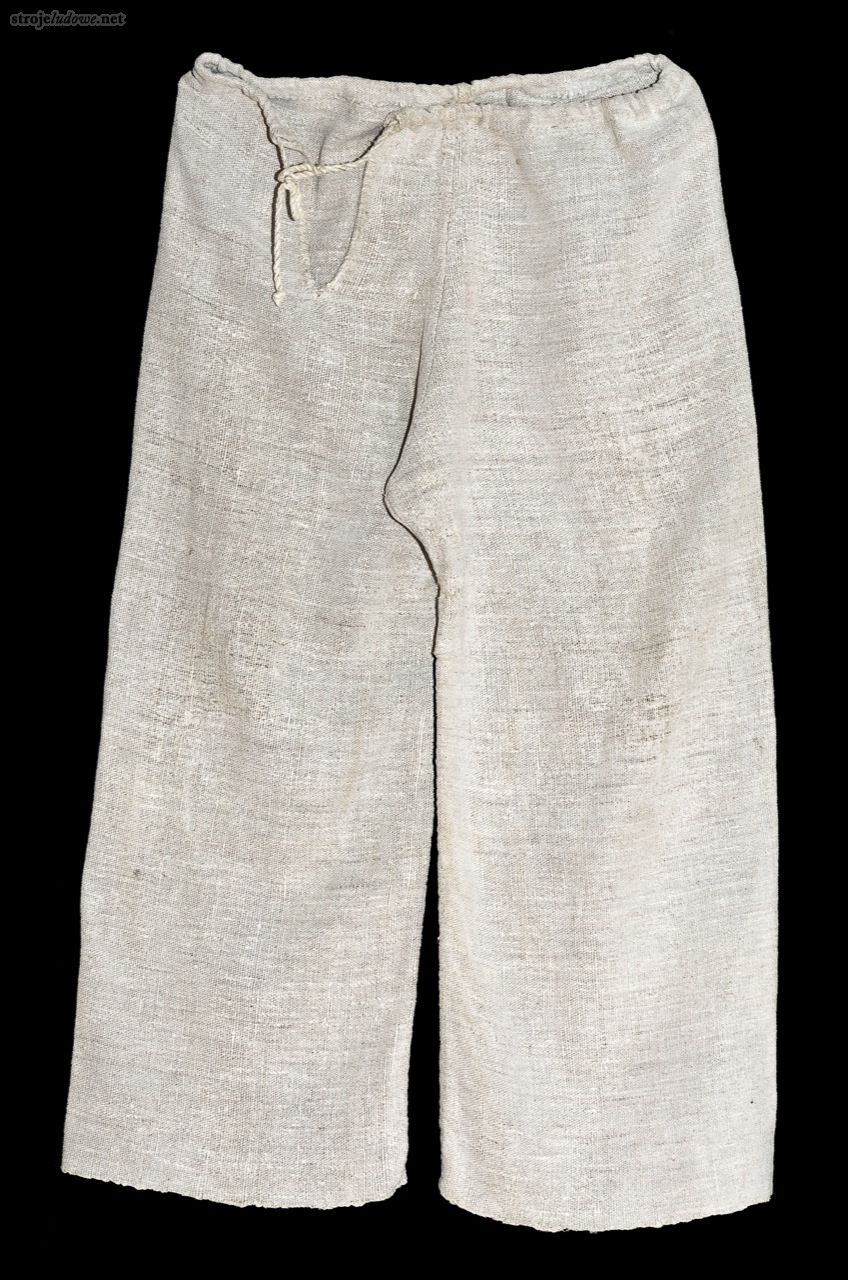 Spodnie lniane, XX w., Łowisko, ze zbiorów Muzeum Etnograficznego w Rzeszowie, fot. G. Stec

Zarówno odświętne jak i codzienne spodnie szyto prawie zawsze z kiepskiego gatunkowo płótna lnianego – tzw. <em>partu</em>. Każdą nogawkę szyto z jednego płata tkaniny, a z przodu, w pasie poszerzał spodnie trójkątny klin. Na boku spodnie miały niewielki rozporek, a ich górna krawędź była podwinięta. Przez powstały, dzięki temu tunelik przeciągano sznurek, którym regulowano obwód w pasie.