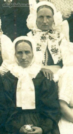 Fragment zdjęcia grupy weselników, ok. 1910 r., ze zbiorów prywatnych

Wstążki dzielono na odświętne i żałobne, znacznie częściej używały ich panny niż mężatki. Za odświętne uważano białe, czerwone i różowe, natomiast fioletowe i niebieskie przynależały do grupy żałobnych lub noszonych w okresie postu. Najstarsze wstążki haftowano ręcznie, po 1910 r. ich miejsce zajęły wyroby wyszywane maszynowo, a jeszcze później o wzorach malowanych. Zawsze jednak, zdobiące je motywy były kwiatowe.