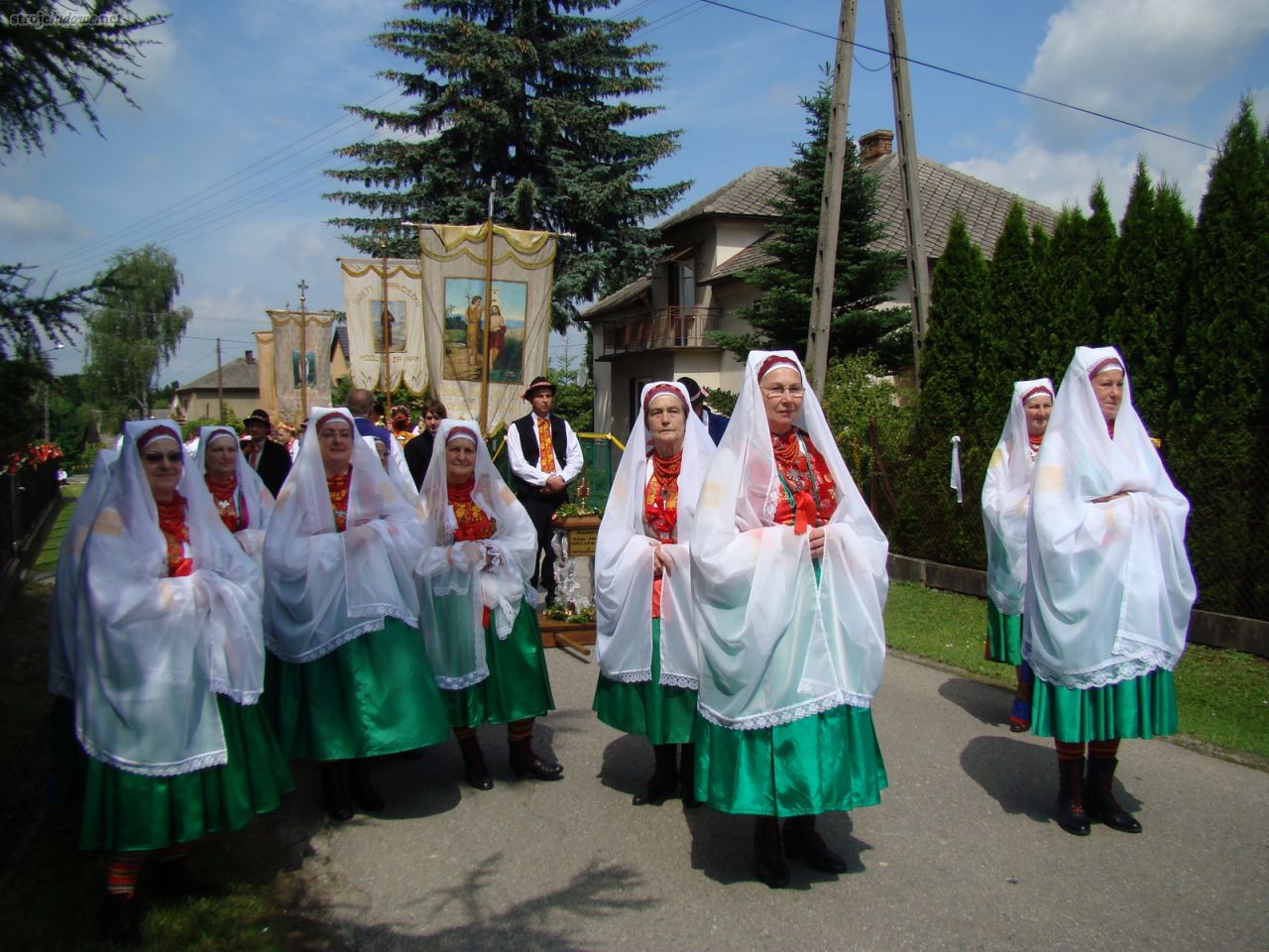 Kobiety w strojach matek chrzestnych zakładanych na Boże Ciało, Wilamowice 2012, fot. Justyna Majerska (Biöetuł) 

Do najstrojniejszych należał oplecek (złoty- <em>gułd gyśtałt</em> lub srebrny -<em>zyłwer gyśtałt</em>) , który przysługiwał pannie młodej lub matce chrzestnej. Oplecki spinano z przodu czerwonymi tasiemkami. Przytwierdzona do oplecka spódnica (<em>rök</em>) w wersji odświętnej wykonana była z czerwonego sukna lub niebieskiej tafty czy jedwabiu, u dołu zdobiona galonem (<em>gułdśnür</em>) czyli pasem misternej koronki wykonanej ze złotego drucika. Ten wariant stroju był najbardziej drogocenny. Charakterystycznym jego elementem jest biały welon, zakładany na bordową <em>związkę</em> oraz siedem czepców, z których ostatni wykonany jest ze złotego brokatu.