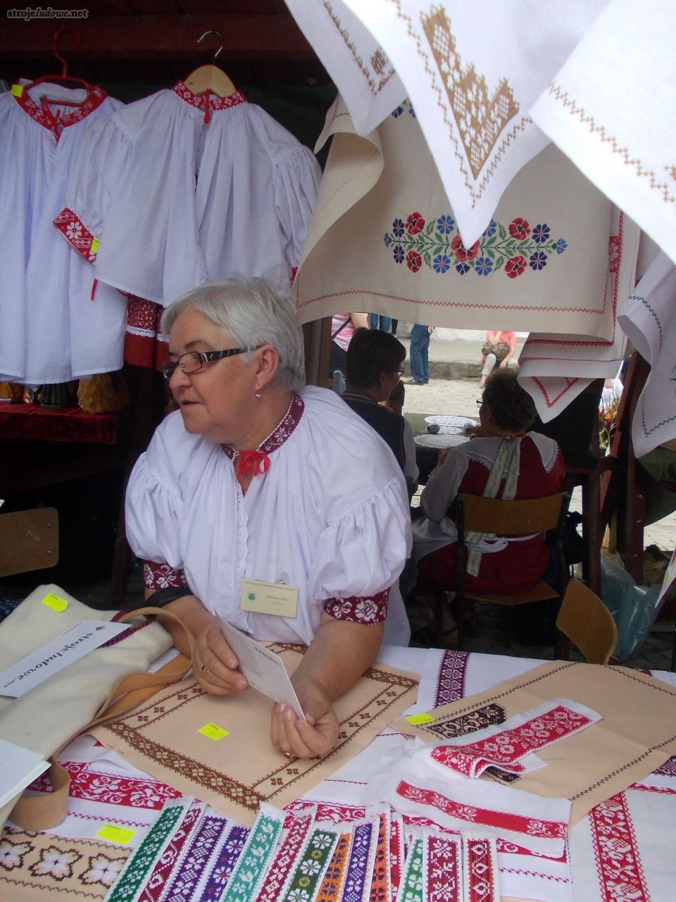 Zuzanna Jancz, twórczyni ludowa, hafciarka z Istebnej przy stoisku podczas kiermaszu towarzyszącego Ogólnopolskiemu Festiwalowi Kapel i Śpiewaków Ludowych w Kazimierzu Dolnym, czerwiec 2014 r., fot. M. Kunecka