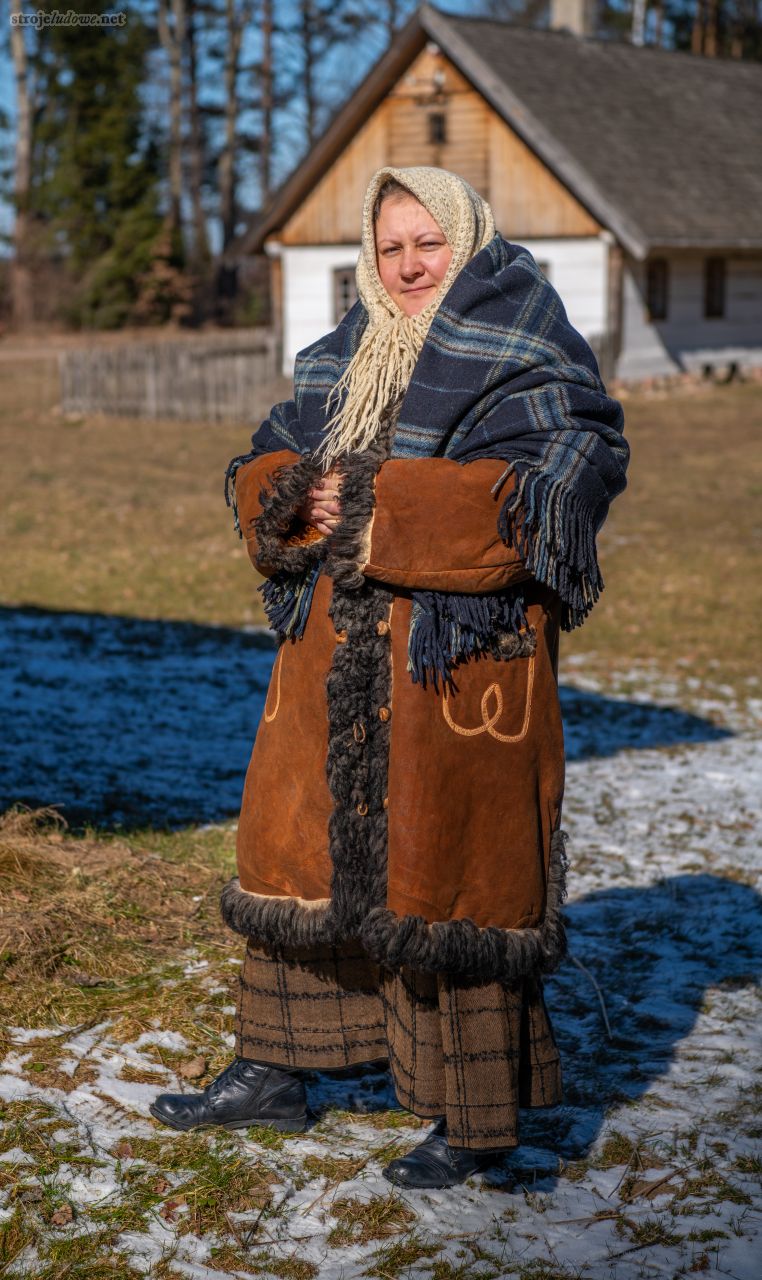 Kobieta z stroju zimowym: kożuchu i chuście, zdjęcie stylizowane na modelce na lata międzywojenne, fot. A. Gaweł, ze zbiorów Podlaskiego Muzeum Kultury Ludowej

Kożuchy noszone przez kobiety były takie same jak te, których używali mężczyźni. Szyto je ze skór owczych. Mogły być one krótkie, sięgające do bioder lub długie do pół łydki. Ich kolorystyka utrzymana była w różnych odcieniach brązu, najczęściej nie były zdobione, niekiedy tylko wzdłuż ich krawędzi haftowano rzędy ściegu Janina lub zakopiańskiego.

Przez dużą część roku kobiety chodziły boso, zaś w dni jesienne i zimowe używały, tak jak i mężczyźni, łapci z łyka lipowego, które zwano postołami lub chodaków szytych z kawałka bydlęcej skóry. Stopę przed ich założeniem starannie owijano lnianą onucą. Do stroju odświętnego zakładały skórkowe trzewiki, wykonywane przez miejscowych szewców.