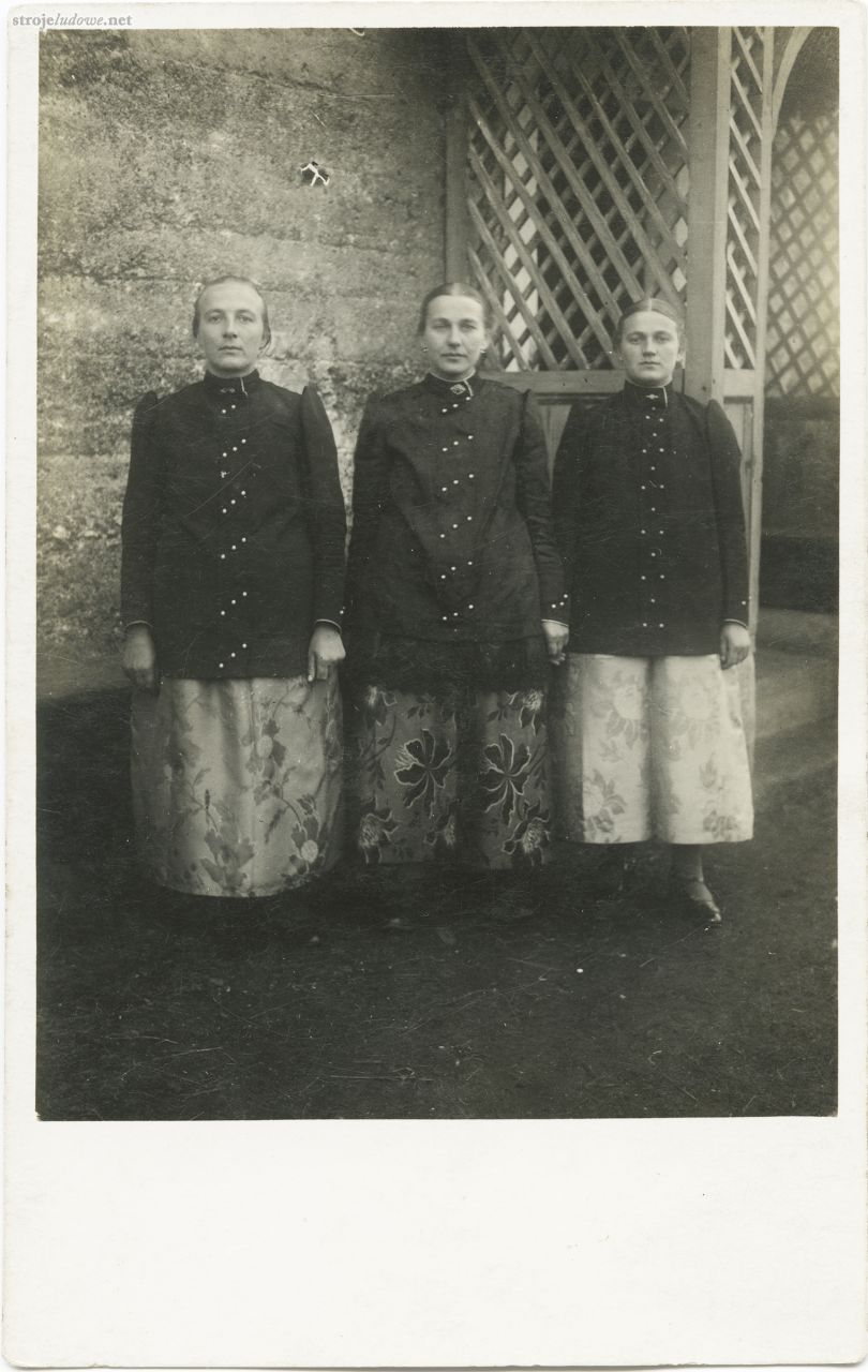 Trzy siostry ubrane w stroje pszczyńskie stojące przed domem, lata 20. XX. w., Żwaków (obecnie dzielnica Tychów), autor nieznany, z kolekcji Muzeum Miejskiego w Tychach