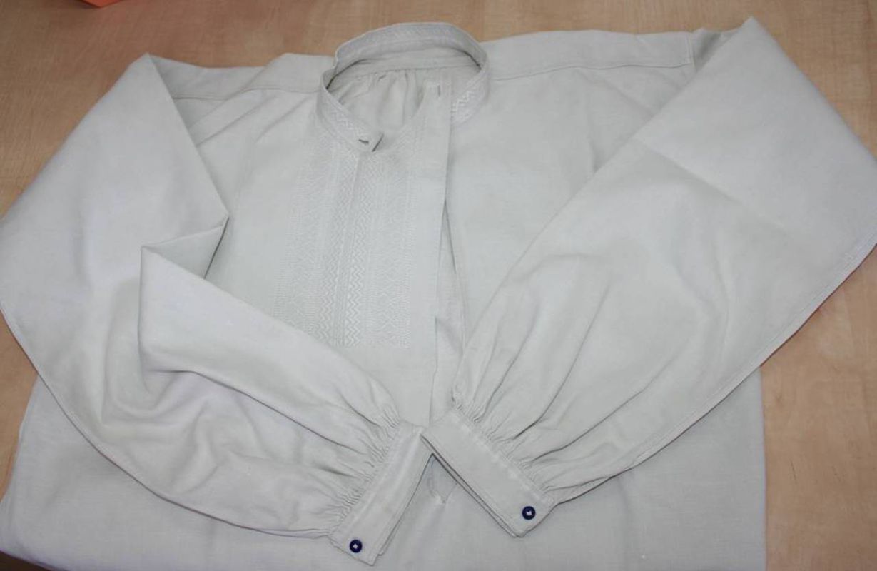 Koszula męska, Piotrkowskie, okres międzywojenny. Ze zbiorów Muzeum Archeologicznego i Etnograficznego w Łodzi, fot. Wł. Pohorecki

Koszula z <em>wykładem </em>weszła w modę na początku XX wieku. Miała krój z tzw. półkarczkiem, długie rękawy, stojący kołnierzyk oraz <em>wykład</em> zapinany na lewym ramieniu lub na boku. Gors, czyli <em>wykład</em> zdobiono haftem białym, przeszywanym lub płaskim. Do zapinania kołnierzyka oraz mankietów używano porcelanowych guziczków.